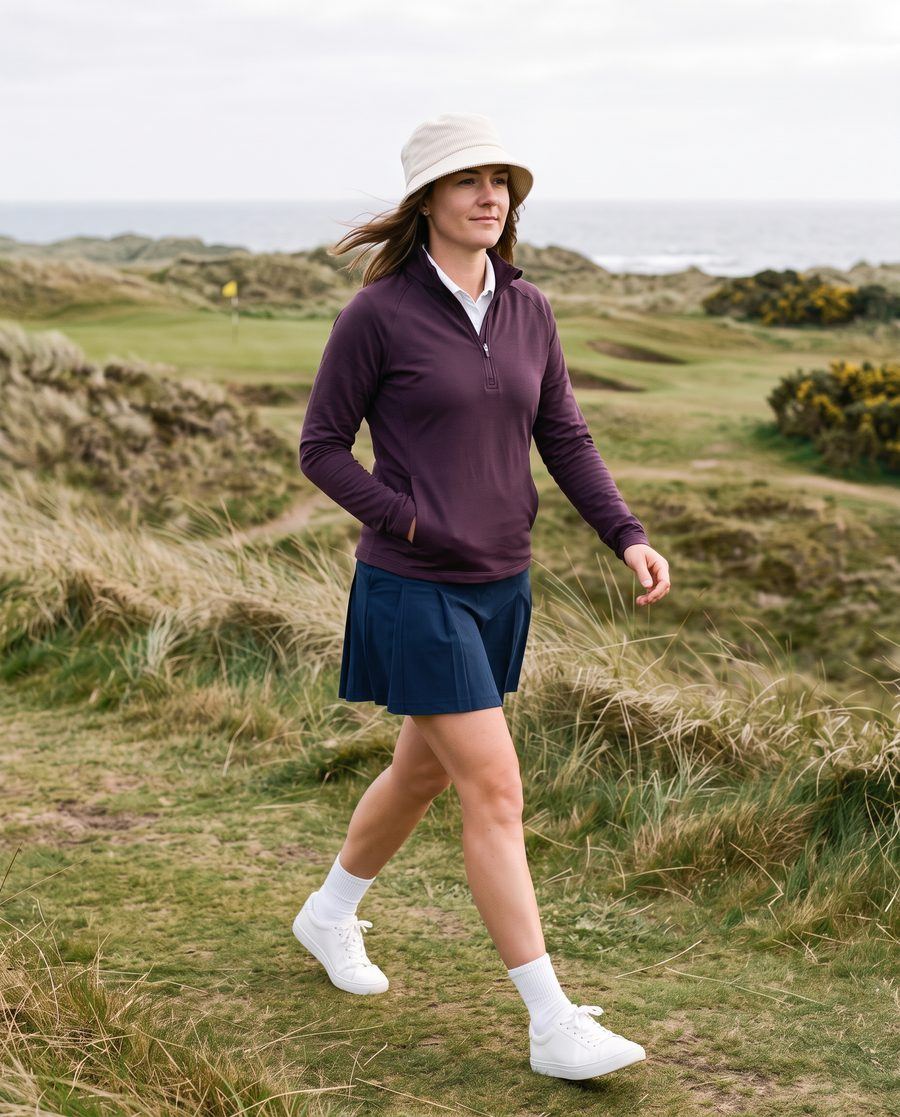 A golfer mid-stride on a links course in overcast light